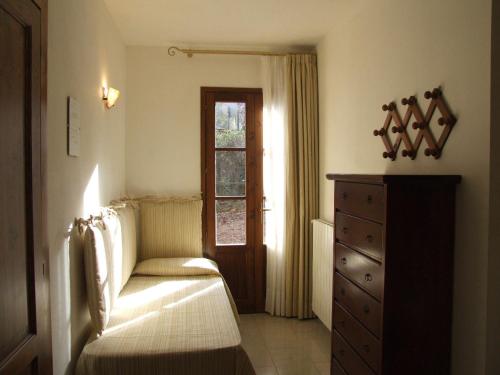 a bedroom with a bed and a dresser and a window at La Quercia-Erica in Sassetta