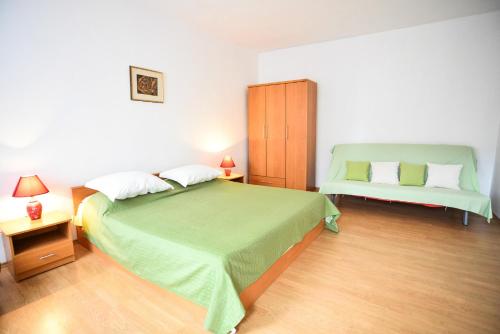 - une chambre avec un grand lit vert et une armoire dans l'établissement Apartments Bobo, à Zadar