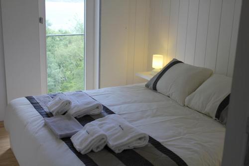 a white bed with towels on it with a window at Moinhos da Corga in Antigo