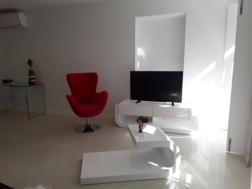 uma sala de estar com uma televisão e uma cadeira vermelha em VIANA é AMOR apartamento no centro histórico em Viana do Castelo