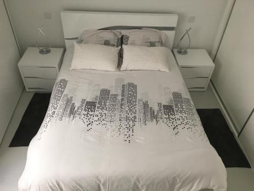 a bedroom with a white bed with two night stands at VIANA é AMOR apartamento no centro histórico in Viana do Castelo