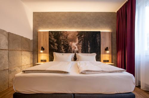 a bedroom with a large white bed with a painting on the wall at Arcus Hotel München Messe in Feldkirchen