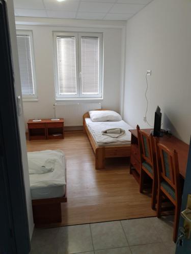 a room with two beds and a desk and two windows at Lánchíd Szálló in Kecskemét