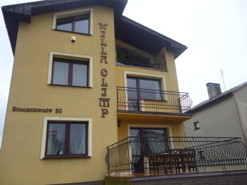 a yellow building with chairs on the balcony at Willa Olimp in Władysławowo