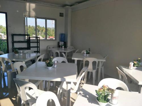 a restaurant with white tables and white chairs at First Baby Bytes Guest House in Siquijor