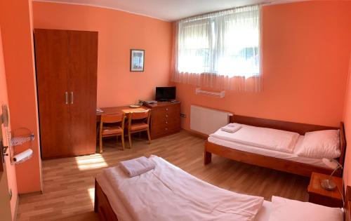 a room with a bed and a desk with a table at Penzion U Splavu in Břeclav