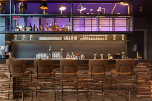 a bar with stools in a room with purple lighting at Postillion Hotel Amsterdam in Amsterdam