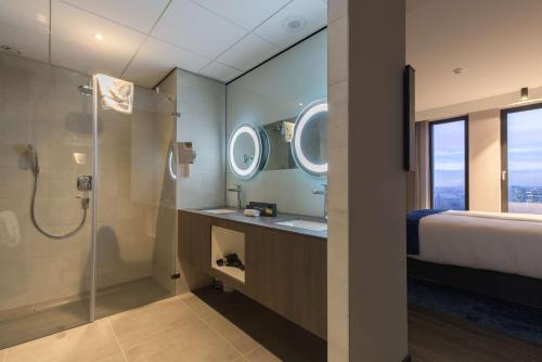 a bathroom with a shower and a bed and a sink at Postillion Hotel Amsterdam in Amsterdam