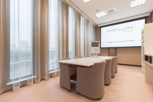 a conference room with a table and chairs and a screen at Postillion Hotel Amsterdam in Amsterdam