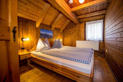 ein Schlafzimmer mit einem Bett in einem Holzzimmer in der Unterkunft Holzblockhäuser Fam. Schabus in Hermagor