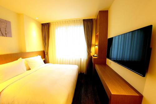 ein Hotelzimmer mit einem Bett und einem Flachbild-TV in der Unterkunft 26 Inn in Yilan