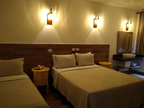 a hotel room with two beds and lights on the wall at Medieval Hotel in Três Corações