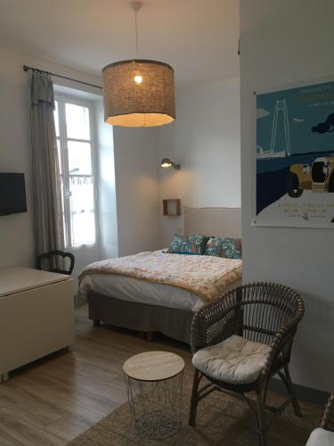 a bedroom with a bed and a chair and a table at les appartements du 10 in Rochefort