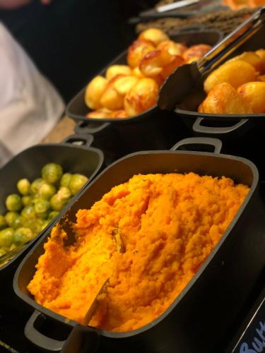 a buffet of different types of food in pans at The Bold Hotel; BW Signature Collection in Southport