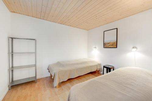 two beds in a room with white walls and wooden ceilings at Adventure Park Apartments in Ringkøbing