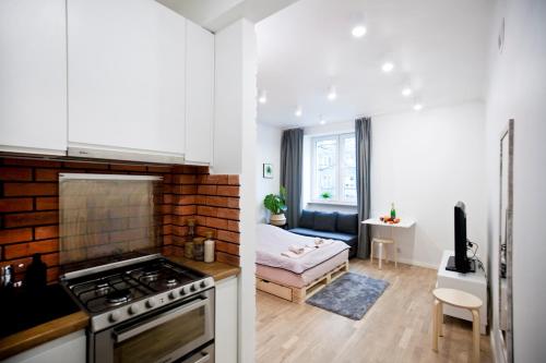 a kitchen with a stove top oven next to a living room at Studio Gaba 2 INTRACO Apartment in Warsaw