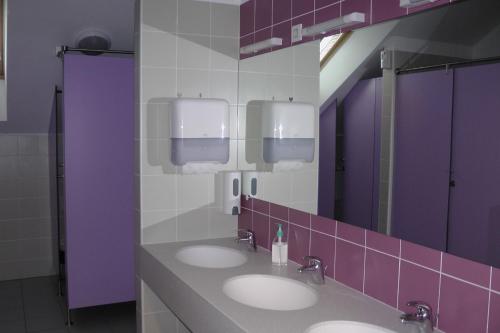 Baño público con 3 lavabos y paredes púrpuras en Youth Hostel Krško, en Krško