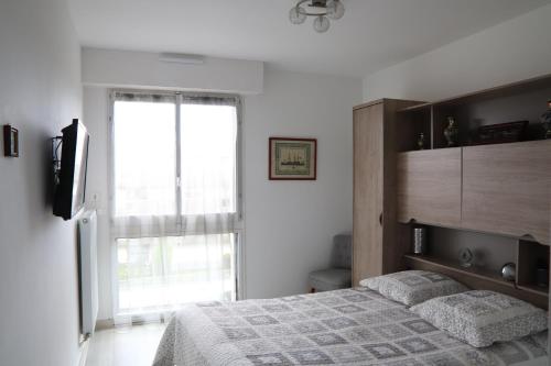 une chambre avec un lit et une grande fenêtre dans l'établissement Le Courtois, à Saint-Malo