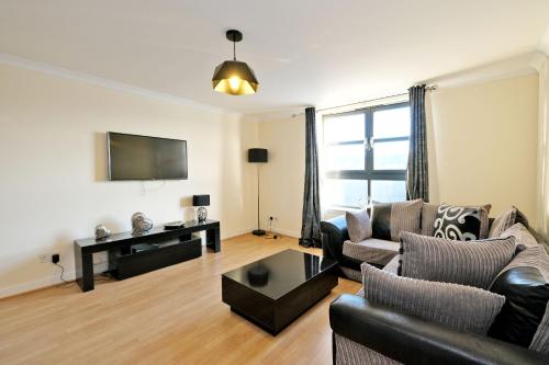 a living room with a couch and a tv at OrangeApartments Riverside Drive,5 Minutes from City Centre in Aberdeen