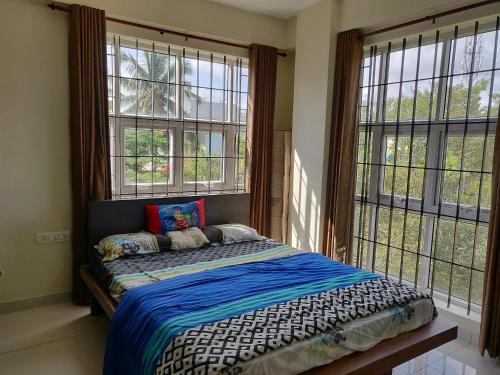 a bedroom with a bed in a room with windows at Swag Apartment in Mysore