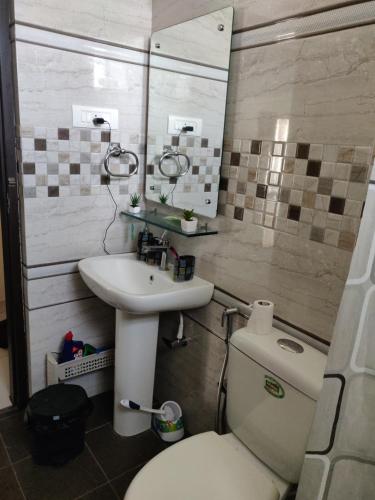 a bathroom with a white toilet and a sink at Swag Apartment in Mysore