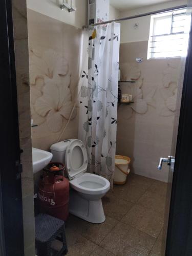 a bathroom with a toilet and a shower curtain at Swag Apartment in Mysore
