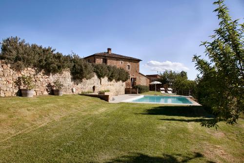 un antico edificio in pietra con piscina in un cortile di Palazzo Massaini - La Pieve a Pienza