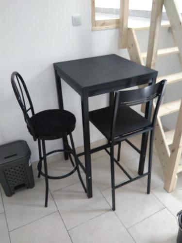 une table noire et deux chaises à côté d'un escalier dans l'établissement jolie appartement centre de Fismes, à Fismes