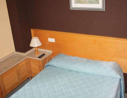 1 dormitorio con 1 cama y mesita de noche con lámpara en Alojamientos ALBOR I, en Gijón