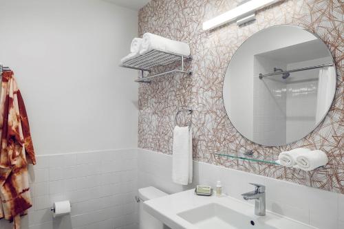 a white bathroom with a sink and a mirror at The Longleaf Hotel in Raleigh