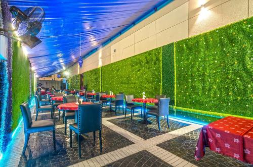 a restaurant with tables and chairs and a green wall at Zain International Hotel in Dubai