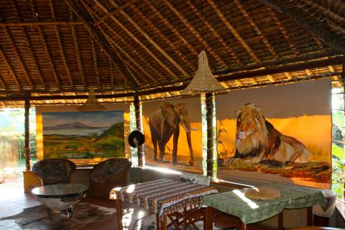 a living room with paintings of lions on the wall at Buffalo's Rest Greenpark-Naivasha in Naivasha