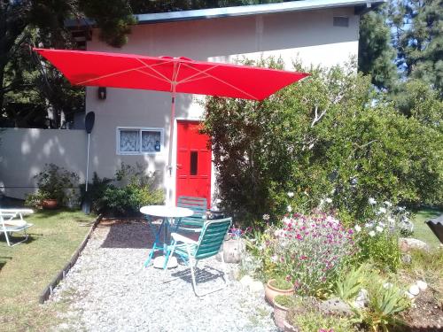 una sombrilla roja sobre una mesa y sillas frente a una casa en San Benito de Palermo en San Carlos de Bariloche