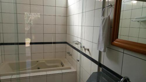 a bathroom with a tub and a sink and a mirror at Hotel Lago das Pedras in Apucarana