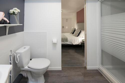 a bathroom with a toilet and a bedroom with a bed at Hôtel Le Lys in Oeting