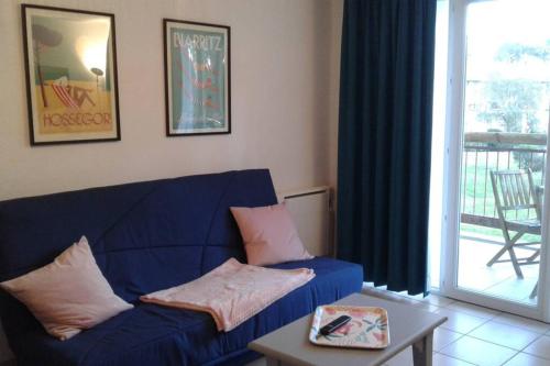 - un salon avec un canapé bleu et une table dans l'établissement T2 Antigua Ondres plage avec piscine et tennis, à Ondres
