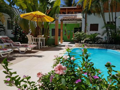 a swimming pool with a yellow umbrella and some flowers at Pousada Sempre Graciosa in Praia do Frances