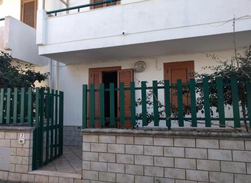 a house with a green fence in front of it at Casa Poesia in Torre dell'Orso