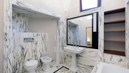 La salle de bains est pourvue d'un lavabo, de toilettes et d'un miroir. dans l'établissement Palazzo Acquaviva - Il Giardino Sospeso, à Lecce