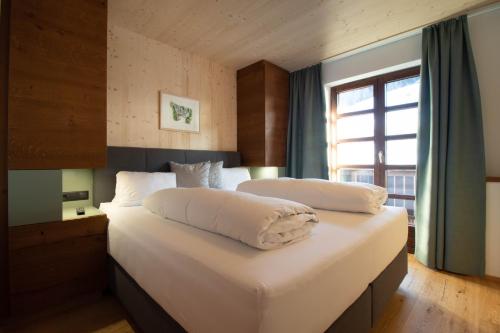um quarto com 2 camas com lençóis brancos e uma janela em Wally Berg-Appartements em Zams