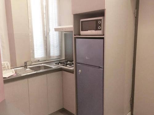 a small kitchen with a microwave on top of a refrigerator at Bilocale vicino Stazione CIR 00015 in Lodi