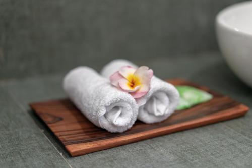 stos ręczników i kwiat na drewnianym talerzu w obiekcie Nusa Indah Onai Hotel w mieście Nusa Lembongan