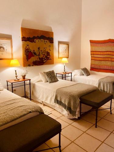 a room with two beds and two tables with lamps at Chañarmuyo Casa de Huéspedes in Chañarmuyo