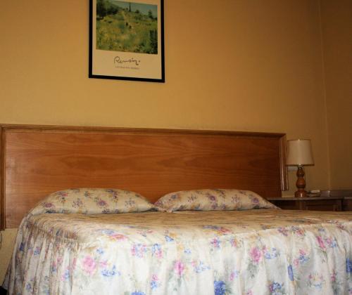 a bed with a wooden headboard and two pillows at Alojamientos ALBOR I in Gijón