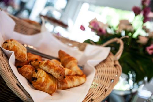 ein Korb mit Brot und Gebäck auf dem Tisch in der Unterkunft Hotel Du Golf in Saint-Étienne