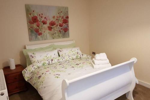 ein Schlafzimmer mit einem weißen Bett mit Blumen darauf in der Unterkunft Sister's Apartment in Llanelli