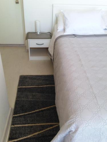 - une chambre avec un lit et une table de chevet dotée d'un couvre-lit blanc dans l'établissement Rooms Katica, à Korčula