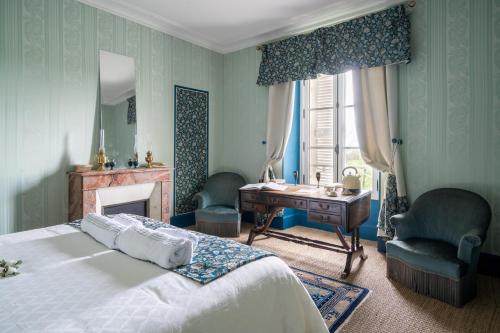 a bedroom with a bed with a desk and two chairs at Château de la Tourlandry in Chemillé