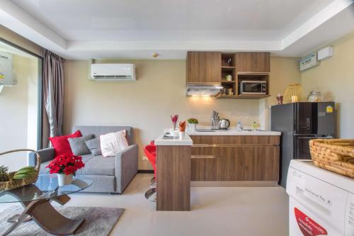 eine Küche und ein Wohnzimmer mit einem Sofa und einem Tisch in der Unterkunft Квартира вид на бассейн NBC S402 by IBG Property in Nai Harn Beach