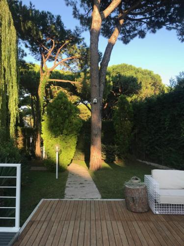 une terrasse en bois avec un arbre dans une cour dans l'établissement Harvey Suites Hotel & Residence, à Lido di Jesolo